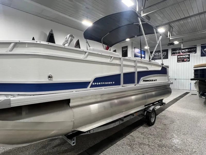 Slide: The Image of 2025 Princecraft Sportfisher 21-2S pontoon boat in showroom, featuring sleek design and canopy. - 2