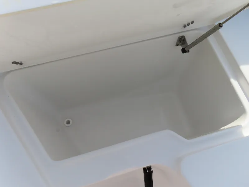 Slide: The Image of 2024 Sea Hunt Ultra 239 SE storage compartment, open lid, white interior. - 10