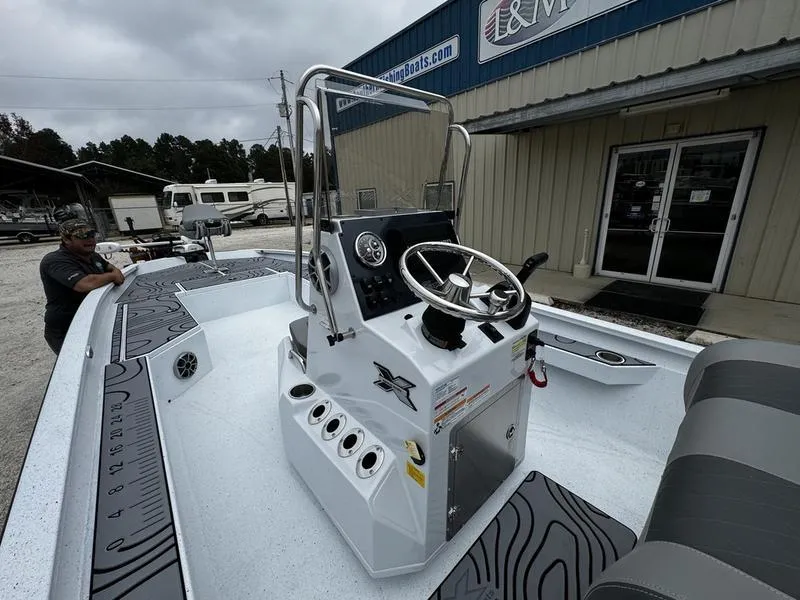 Slide: The Image of 2025 Xpress H24B boat with steering console, parked outside a dealership. - 1
