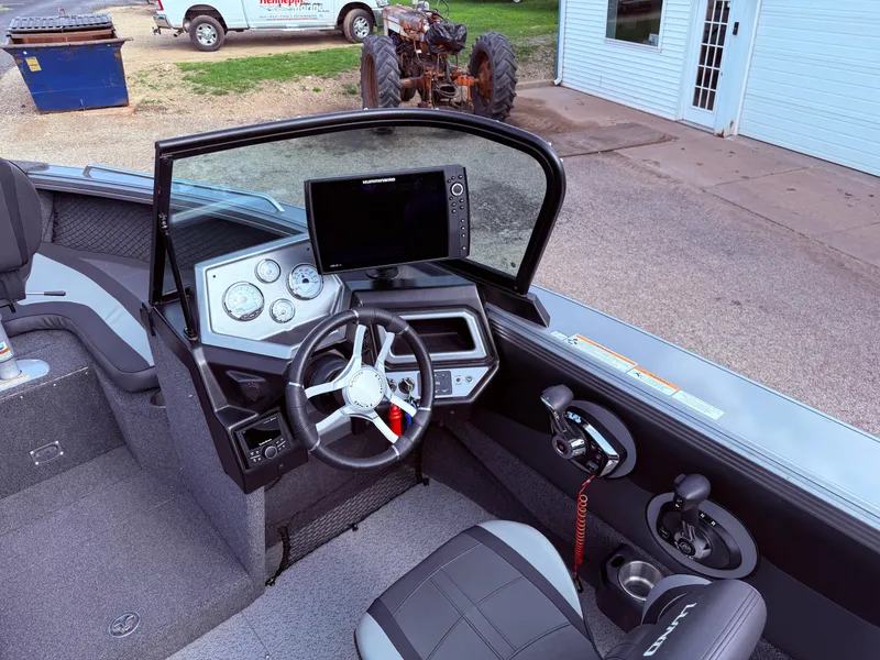 Slide: The Image of 2023 Lund 2275 Baron boat cockpit with steering wheel, gauges, and navigation screen. - 14