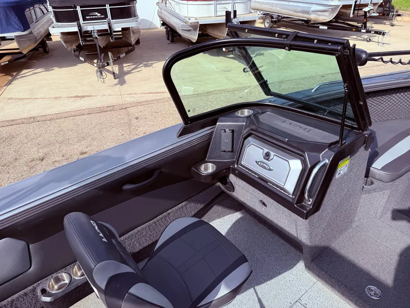 Slide: The Image of 2023 Lund 2275 Baron boat interior with seating and dashboard, parked near other boats. - 19
