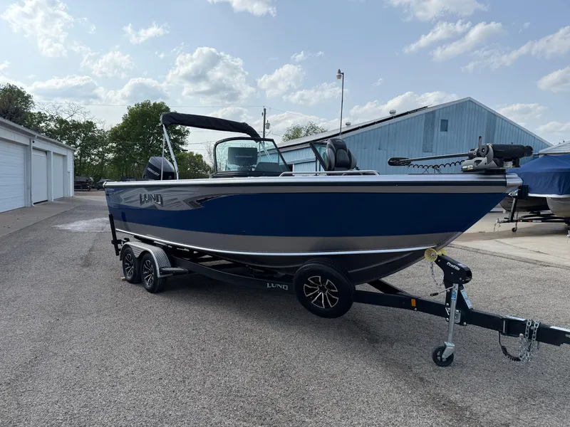 Slide: The Image of 2023 Lund 2275 Baron boat on trailer, parked outdoors near storage units. - 2