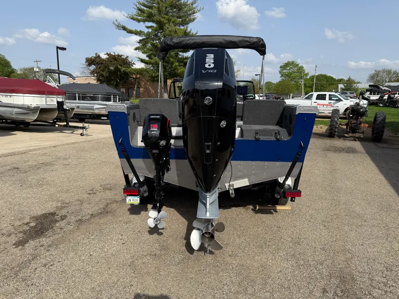 Slide: The Image of 2023 Lund 2275 Baron boat with dual outboard motors, parked on a sunny day. - 5