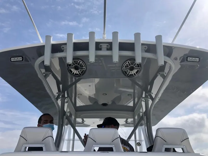 Slide: The Image of 2020 SeaVee 370z boat helm with T-top, rod holders, and speakers under a blue sky. - 10