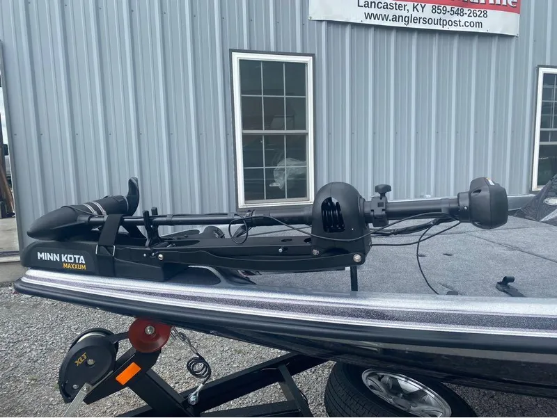 Slide: The Image of 2025 Phoenix 518 Pro boat with Minn Kota Maxxum trolling motor, parked outside a building. - 13