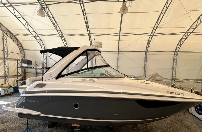 Slide: The Image of 2021 Regal 2800 Express boat in storage, side view, under a large canopy. - 0