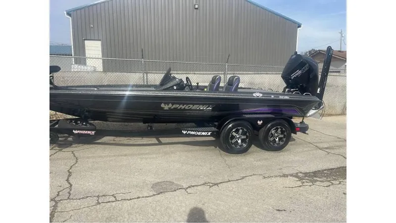 Slide: The Image of 2025 Phoenix 920 Elite boat on trailer, parked outdoors near a metal building. - 11