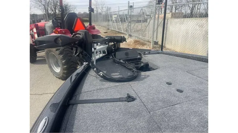 Slide: The Image of 2025 Phoenix 920 Elite boat deck with equipment, parked near a fence and tractor. - 7