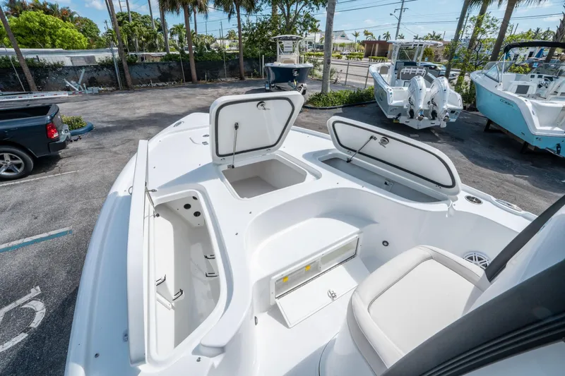 Slide: The Image of 2025 Sea Hunt BX 22 BR boat with open storage compartments, parked outdoors. - 25