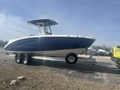 Slide: The Image of 2025 Yamaha Boats 252 FSH Sport on trailer, blue and white hull, parked outdoors. - 5