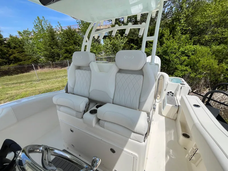 Slide: The Image of 2025 Key West 291 FS boat with luxurious white seating and helm, surrounded by greenery. - 2