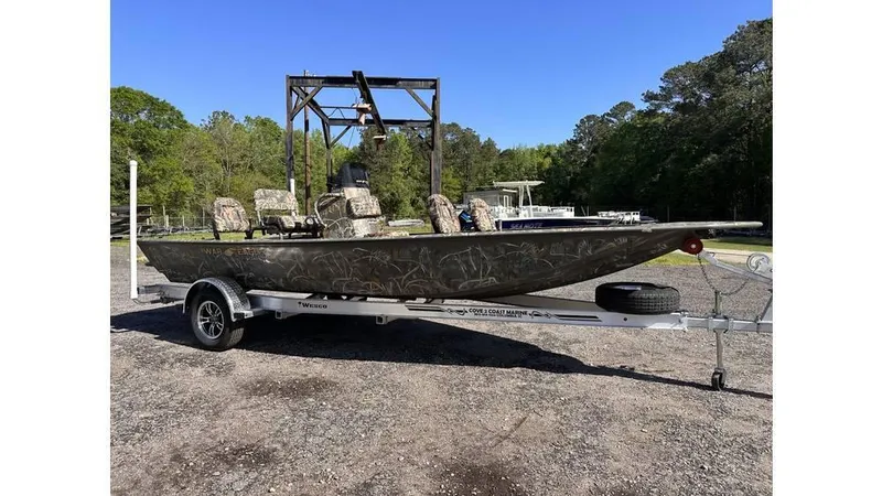 Slide: The Image of 2025 War Eagle 961 Blackhawk boat on trailer, parked outdoors, surrounded by trees. - 10