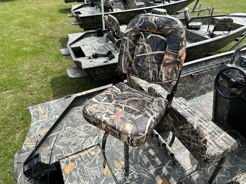 Slide: The Image of 2025 War Eagle 961 Blackhawk boat with camouflage seating, parked on grass. - 6