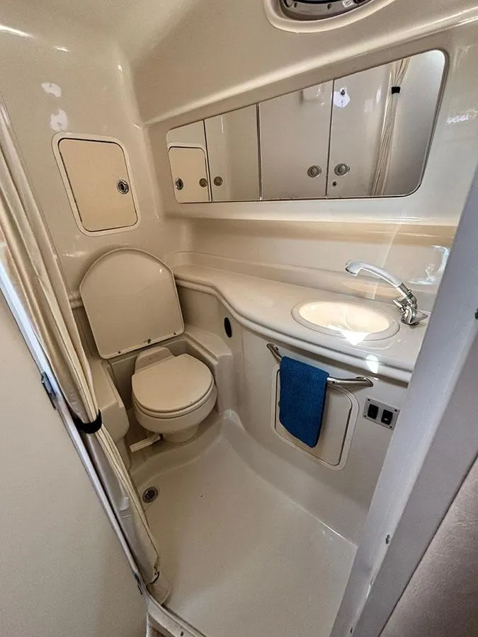 Slide: The Image of 2006 Sea Ray 320 Sundancer bathroom with toilet, sink, and storage cabinets. - 14