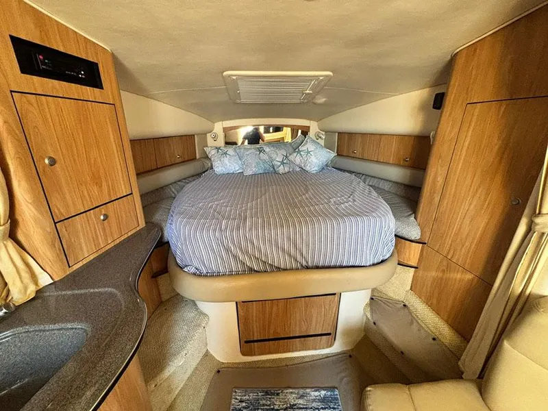 Slide: The Image of 2006 Sea Ray 320 Sundancer cabin interior with bed and wooden cabinetry. - 17