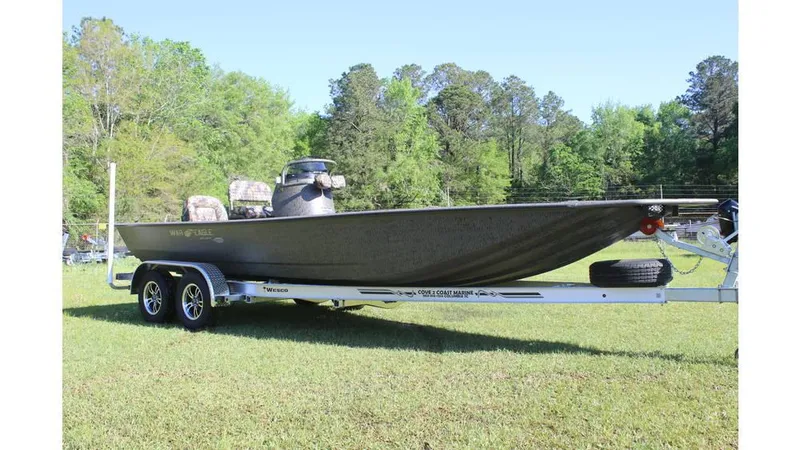 Slide: The Image of 2025 War Eagle 2170 Blackhawk boat on trailer, parked on grass with trees in background. - 8