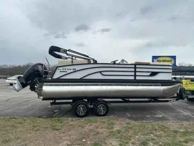 Slide: The Image of 2025 Lowe SS 210 WT pontoon boat on trailer, parked outdoors under cloudy sky. - 4