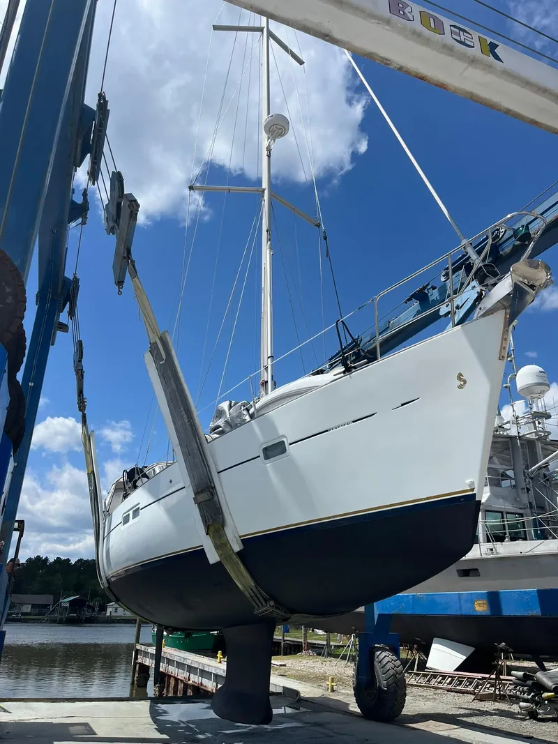 Slide: The Image of 2007 Beneteau 423 sailboat in dry dock, suspended for maintenance under a clear blue sky. - 8