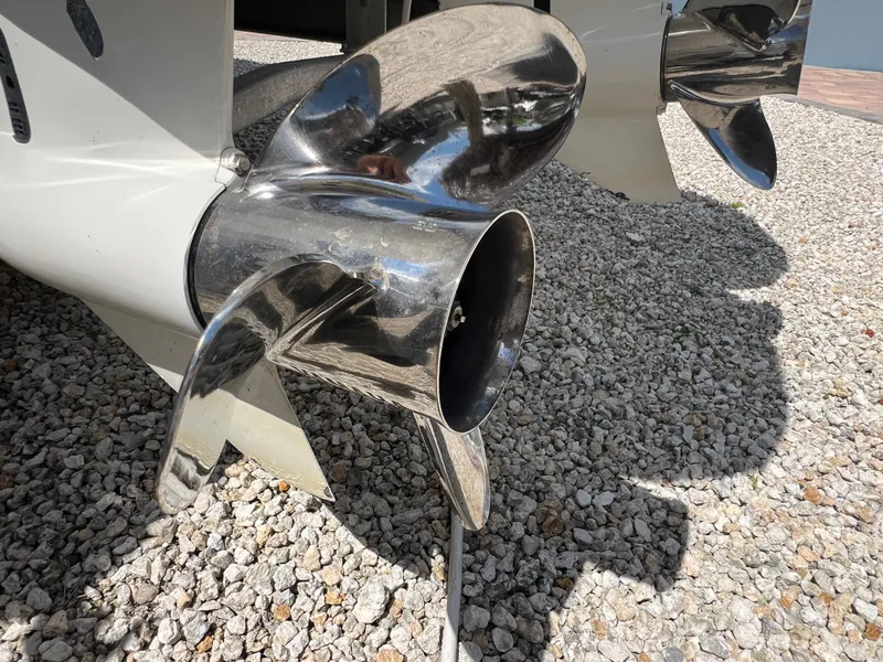 Slide: The Image of 2016 Pursuit S 280 Sport boat propellers on gravel surface, reflecting sunlight. - 16