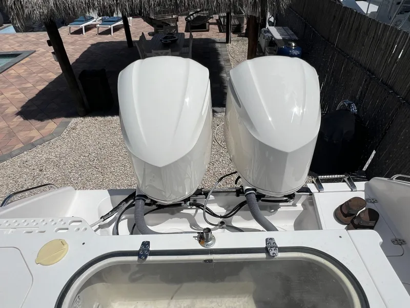 Slide: The Image of 2016 Pursuit S 280 Sport boat with dual outboard engines, docked near a poolside area. - 23