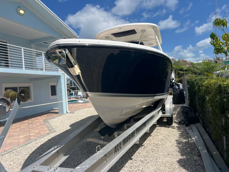 Slide: The Image of 2016 Pursuit S 280 Sport boat on trailer, parked beside a modern house under a blue sky. - 4