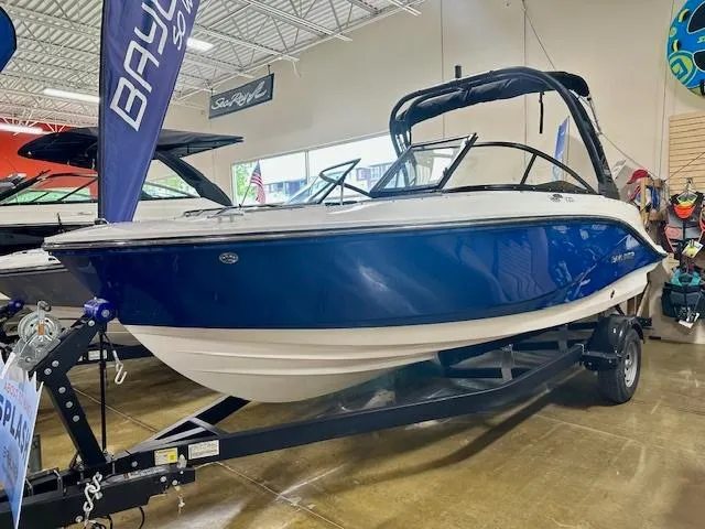 Slide: The Image of 2025 Bayliner V20i boat on display in showroom, blue and white design. - 1