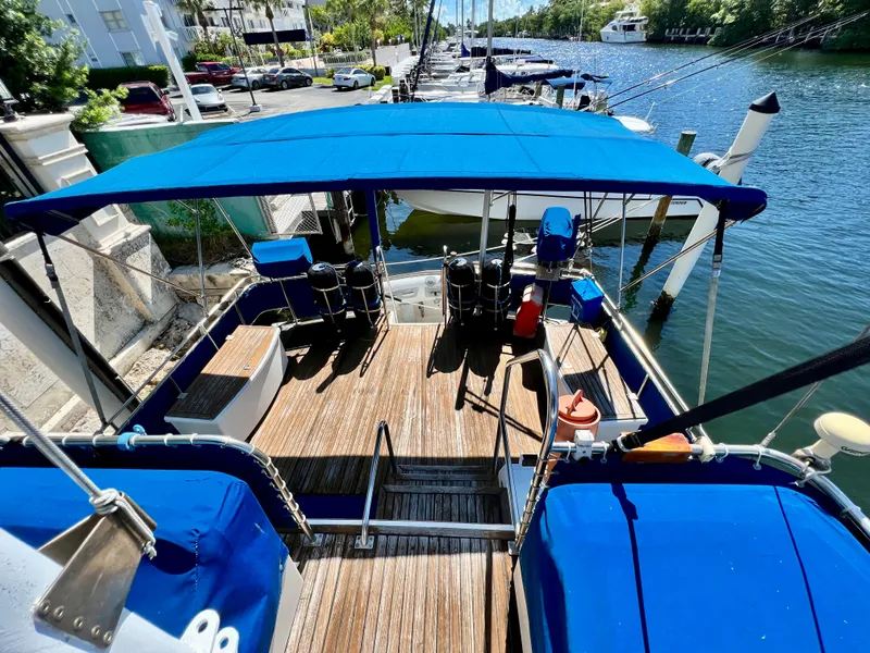Slide: The Image of 1985 Grand Banks 42 Motoryacht with blue canopy docked by a scenic waterfront. - 10