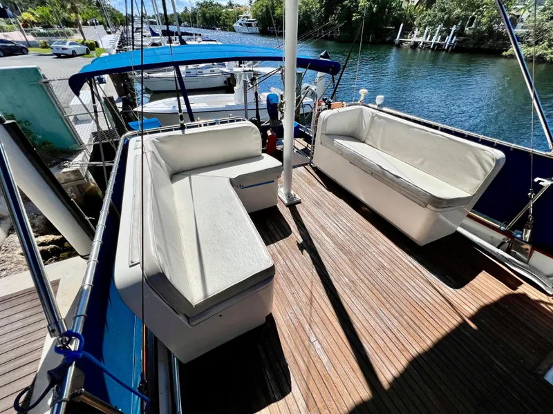 Slide: The Image of 1985 Grand Banks 42 Motoryacht deck with cushioned seating and blue canopy. - 12