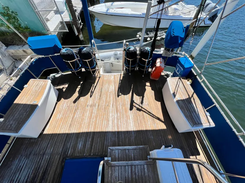 Slide: The Image of 1985 Grand Banks 42 Motoryacht deck with wooden flooring and seating, docked by the water. - 14
