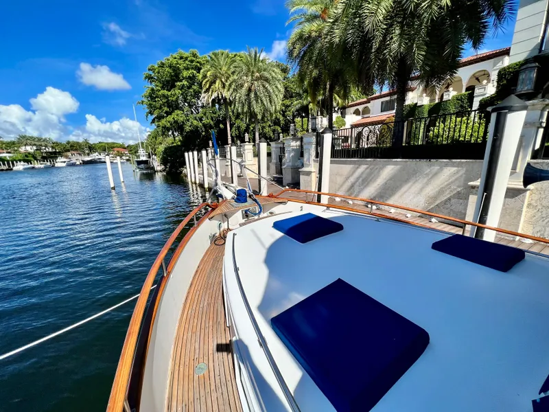 Slide: The Image of 1985 Grand Banks 42 Motoryacht docked by palm trees and waterfront homes. - 15
