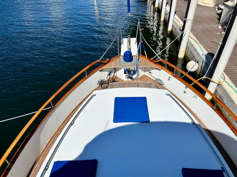 Slide: The Image of 1985 Grand Banks 42 Motoryacht bow view with blue cushions, docked at marina. - 16
