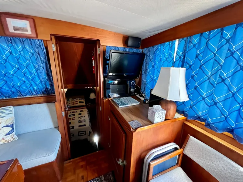 Slide: The Image of Interior of 1985 Grand Banks 42 Motoryacht with blue curtains, TV, and cozy seating area. - 21