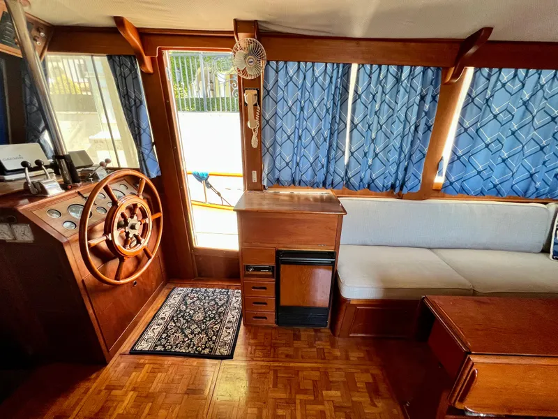 Slide: The Image of Interior of 1985 Grand Banks 42 Motoryacht with wooden helm, blue curtains, and seating area. - 22