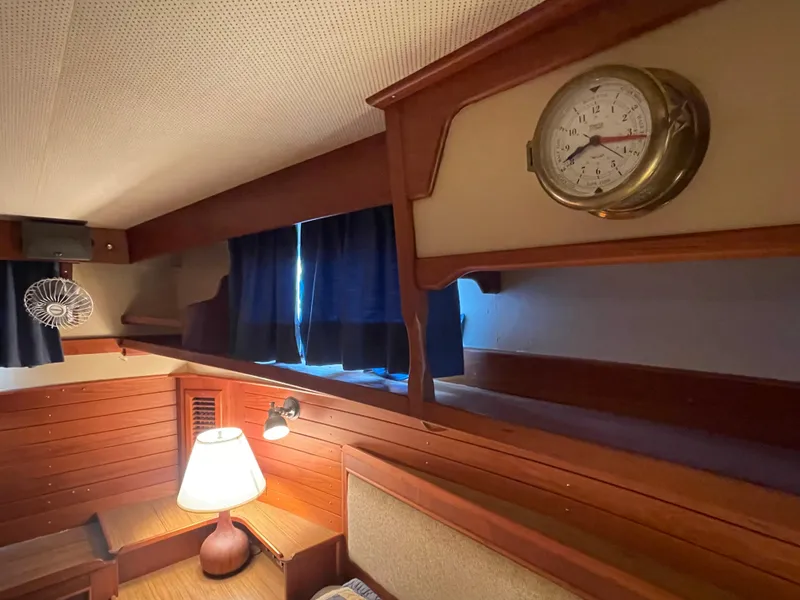 Slide: The Image of 1985 Grand Banks 42 Motoryacht interior with wood paneling, lamp, and nautical clock. - 24