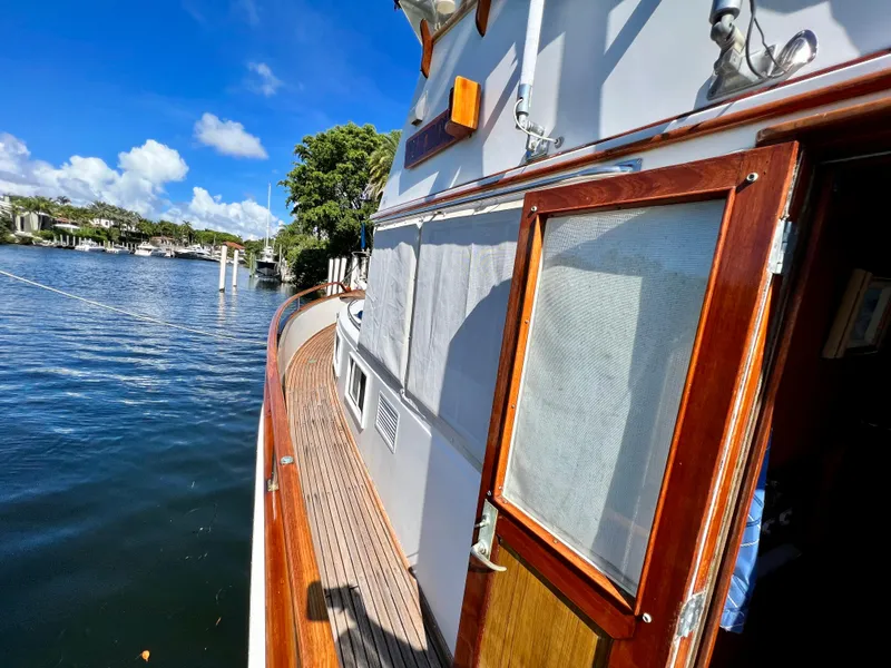 Slide: The Image of 1985 Grand Banks 42 Motoryacht with wooden deck, docked by calm waters under a clear blue sky. - 39