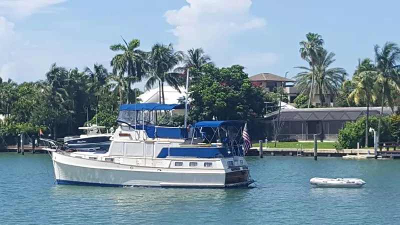 Slide: The Image of 1985 Grand Banks 42 Motoryacht on tranquil water, surrounded by lush palm trees. - 4