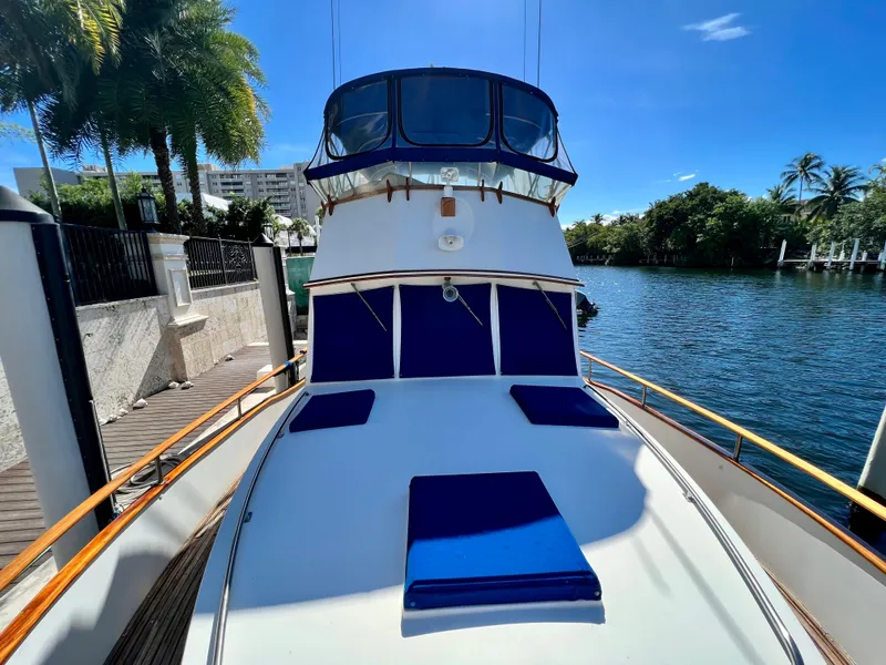Slide: The Image of 1985 Grand Banks 42 Motoryacht docked, featuring blue cushions and a sunny waterfront view. - 5