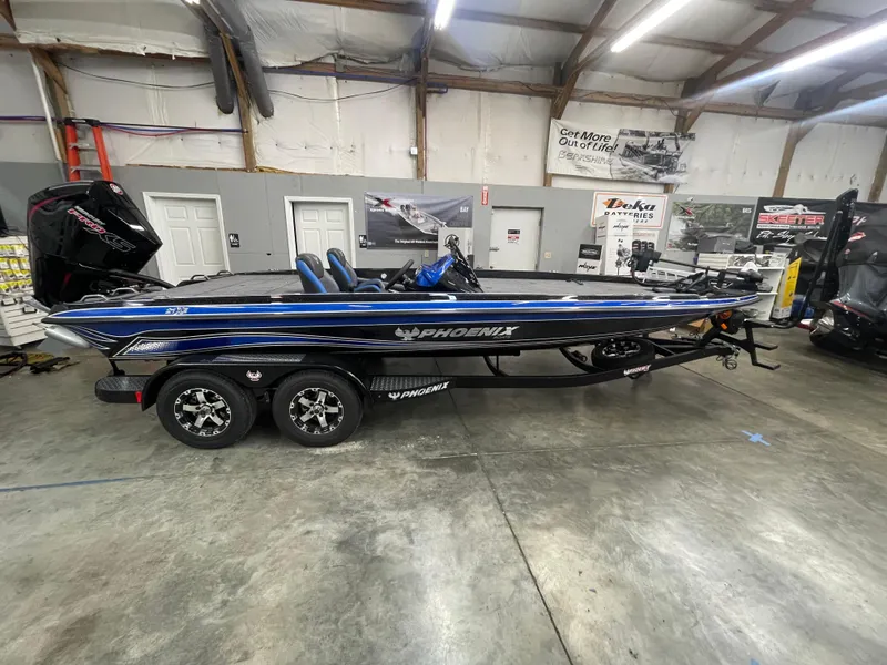 Slide: The Image of 2025 Phoenix 21 XE boat in a showroom, featuring sleek design and dual axle trailer. - 1