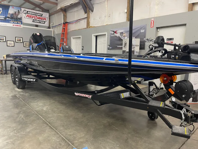 Slide: The Image of 2025 Phoenix 21 XE boat in showroom, black and blue design, on trailer. - 5