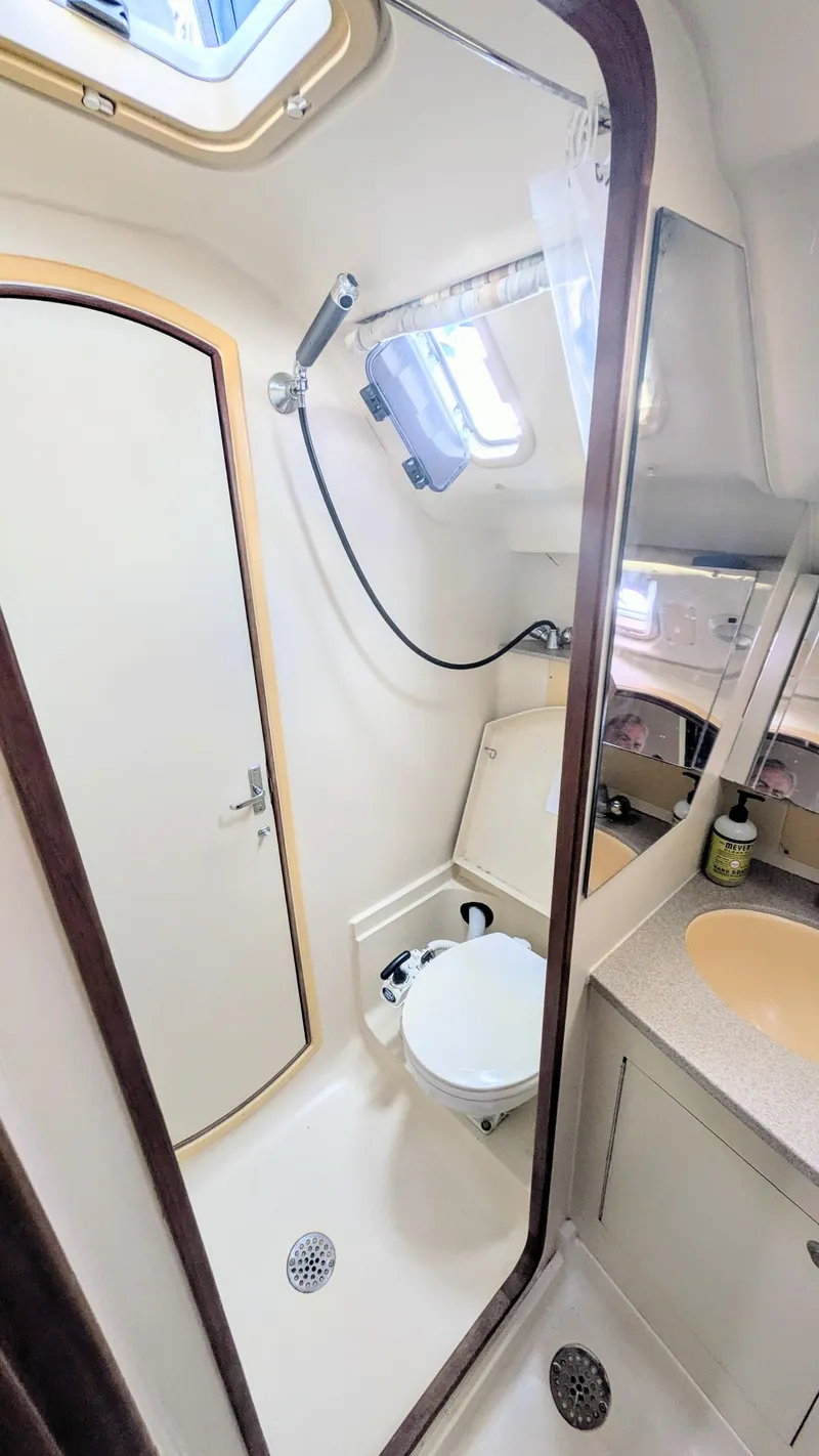 Slide: The Image of Compact bathroom in a 2001 Hunter 380 yacht, featuring a shower, toilet, and sink. - 23