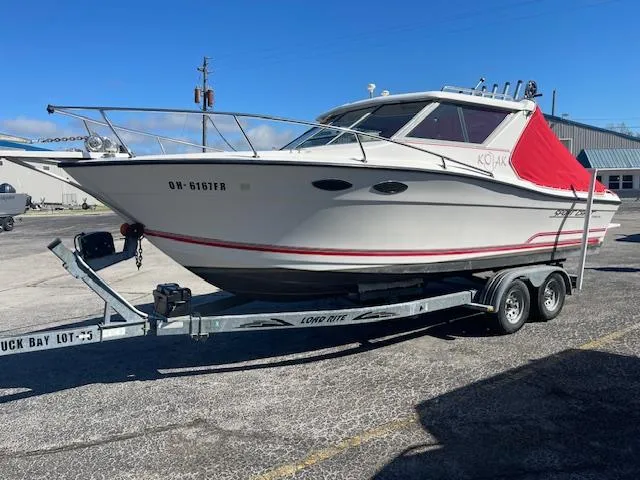 Slide: The Image of 1998 Sport-Craft 232 boat on trailer, white with red accents, parked outdoors. - 3