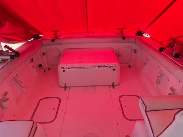 Slide: The Image of 1998 Sport-Craft 232 boat interior under red canopy, featuring seating and storage compartments. - 7