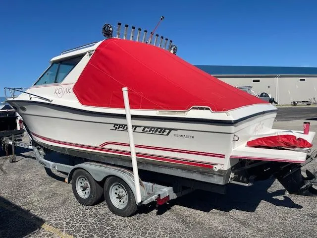 Slide: The Image of 1998 Sport-Craft 232 boat with red cover on a trailer, parked outdoors. - 8