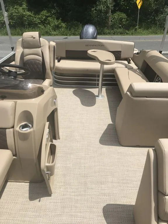 Slide: The Image of 2019 Bennington 23 SSBX pontoon boat interior with beige seating and table. - 2