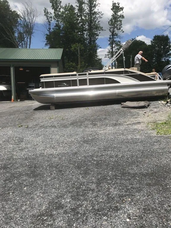 Slide: The Image of 2019 Bennington 23 SSBX pontoon boat on gravel near a garage, under a partly cloudy sky. - 5