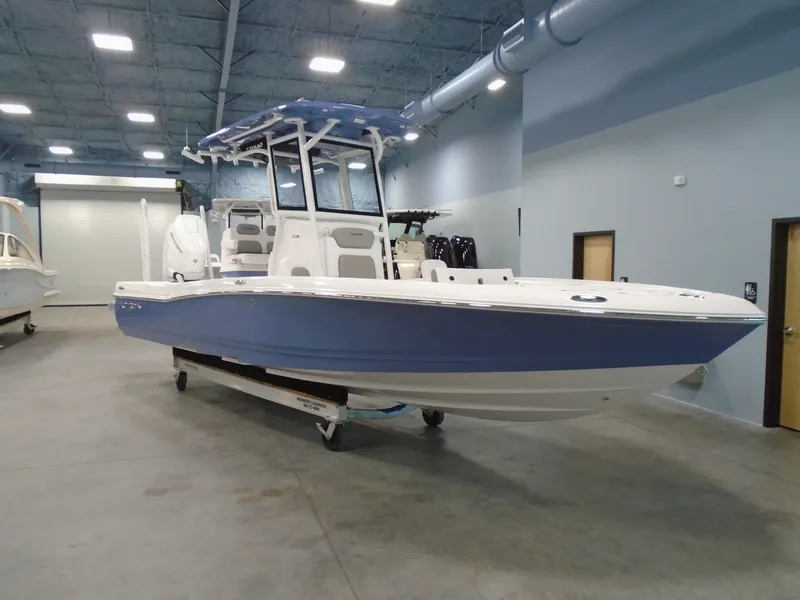 Slide: The Image of 2026 Caymas 26 HB boat on trailer, parked outdoors near a building. - 2