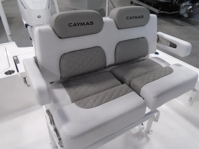 Slide: The Image of 2026 Caymas 26 HB boat console with T-top and rod holders, set against a forested backdrop. - 8