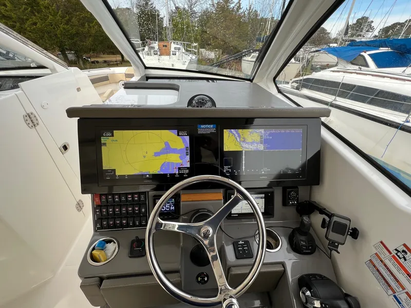 Slide: The Image of Cockpit of 2021 Pursuit DC 365 boat with navigation screens and steering wheel. - 19