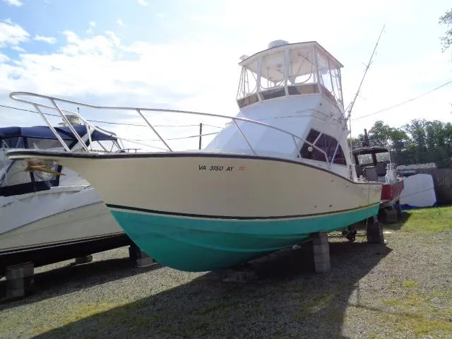 Slide: The Image of 1999 Albemarle 325 Convertible boat on dry dock, white and teal hull, sunny day. - 0