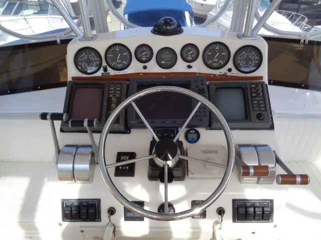 Slide: The Image of 1999 Albemarle 325 Convertible helm with gauges, steering wheel, and navigation equipment. - 13